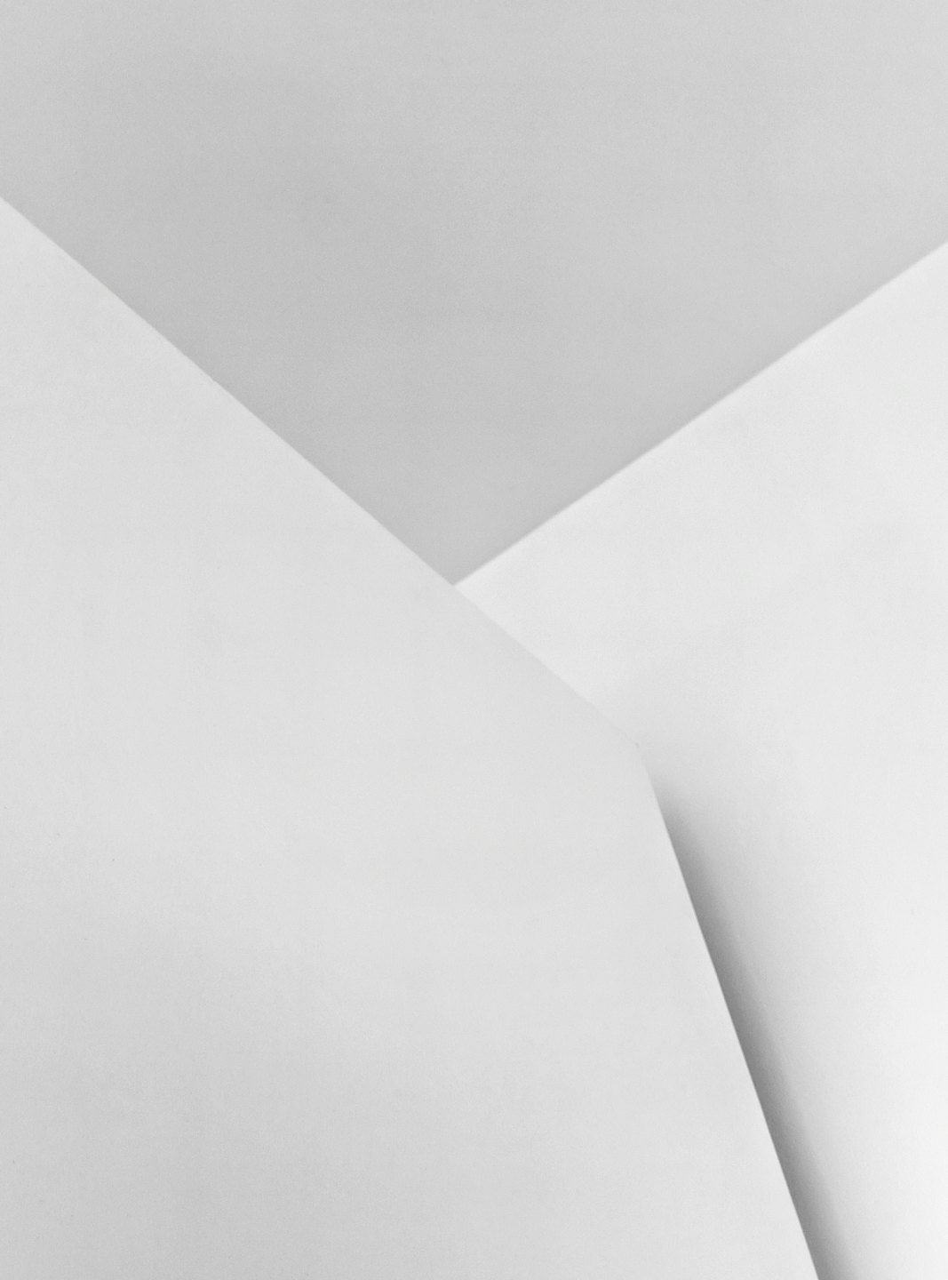 Piani geometrici bianchi e grigi intersecati formano una struttura architettonica.
